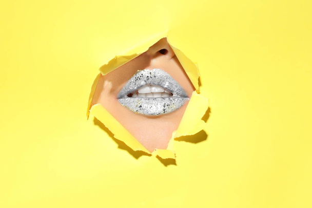 View of beautiful young woman with creative lips makeup through hole in color paper - Фото, зображення