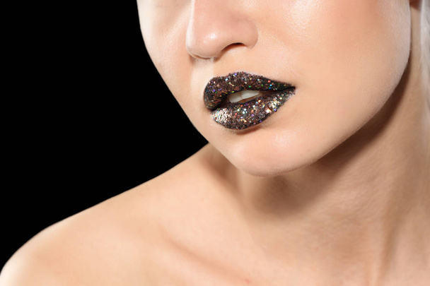 Beautiful young model with creative lips makeup on black background - Foto, afbeelding