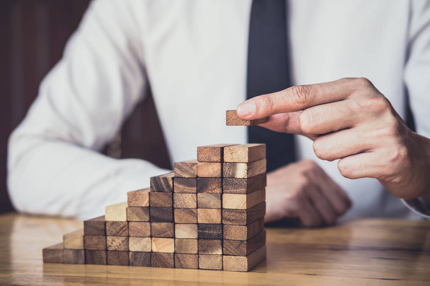 Risk To Make Business Growth Concept With Wooden Blocks, hand of man has piling up and stacking a wooden block, Alternative risk concept, plan and strategy in business. - 写真・画像