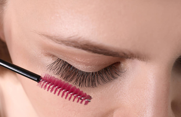 Attractive young woman applying mascara on her eyelashes, closeup - Foto, afbeelding