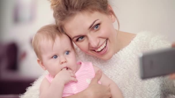 Smiling mother making selfie photo with baby girl. Woman with kid mobile photo - Metraje, vídeo