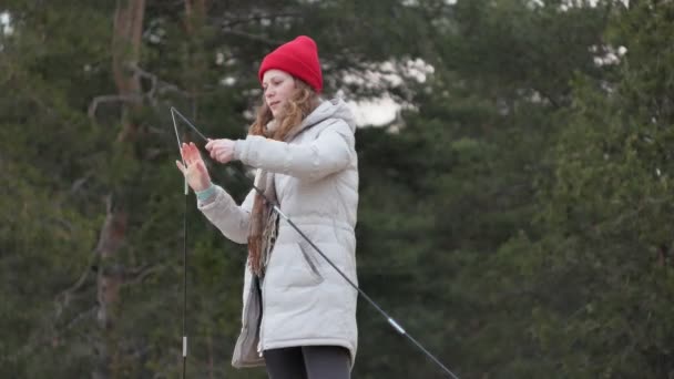 Ελκυστικών τουριστικών νεαρή γυναίκα σε ένα κόκκινο καπέλο συλλέγει μια τουριστική σκηνή κοντά στο δάσος στην ακτή - Πλάνα, βίντεο