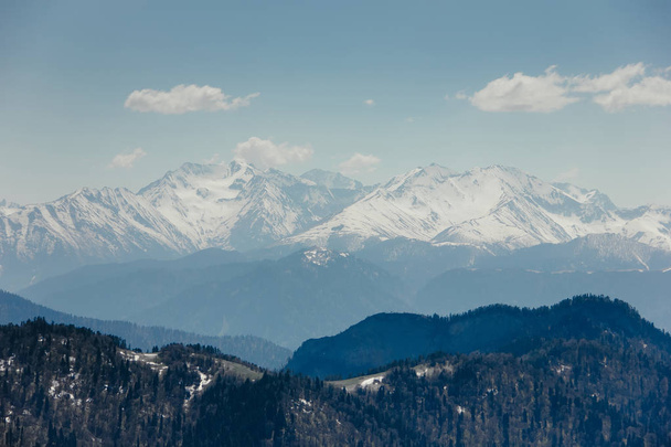 Kar, mavi gökyüzü, Caucasus üzerinde beyaz bulutlar dağların zirveleri ile kaplı - Fotoğraf, Görsel