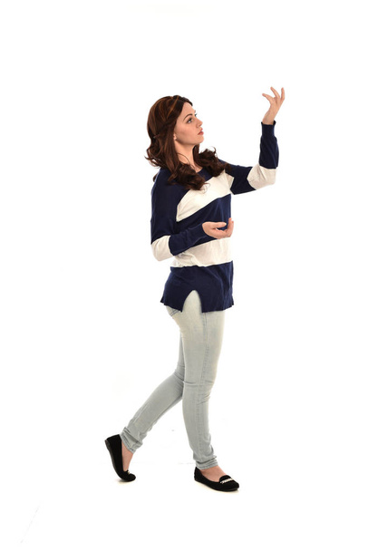 full length portrait of girl wearing striped blue and white jumper and jeans. standing pose on white studio background. - Zdjęcie, obraz
