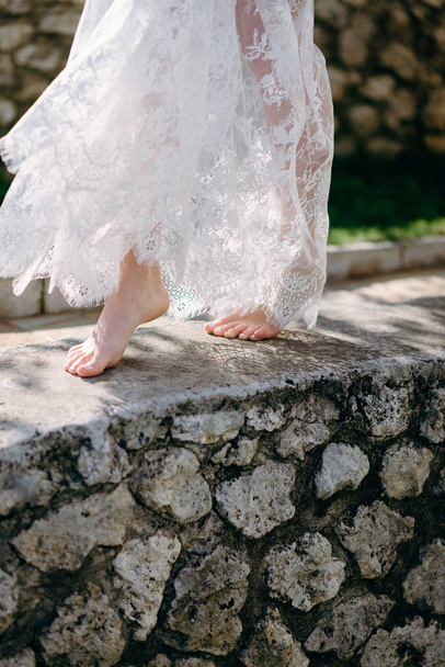 Low section view of woman in lace negligee walking on stone path - Photo, Image