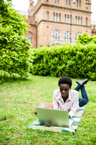 Laughing casual student lying on grass taking notes on campus at college - Foto, Imagem