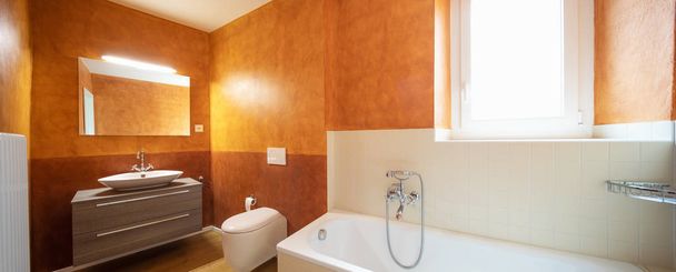 Bathroom with modern finishes and orange walls. Nobody inside - Фото, зображення