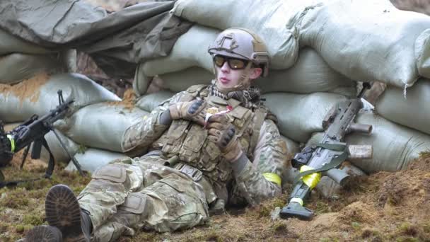 Soldados en camuflaje con armas militares descansan en el refugio del bosque, el concepto militar
 - Imágenes, Vídeo