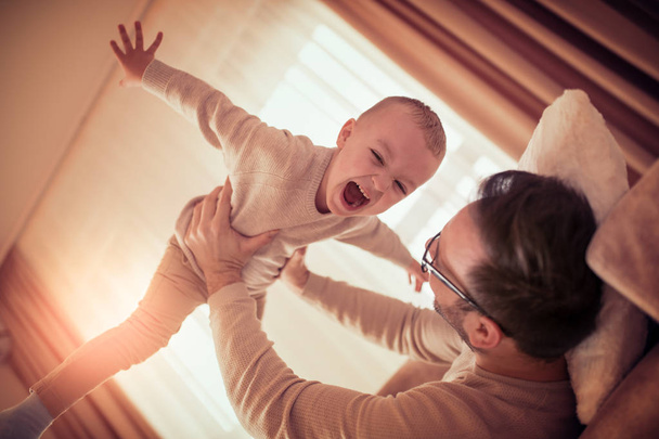 Father and son smiling spending time together at home. - 写真・画像