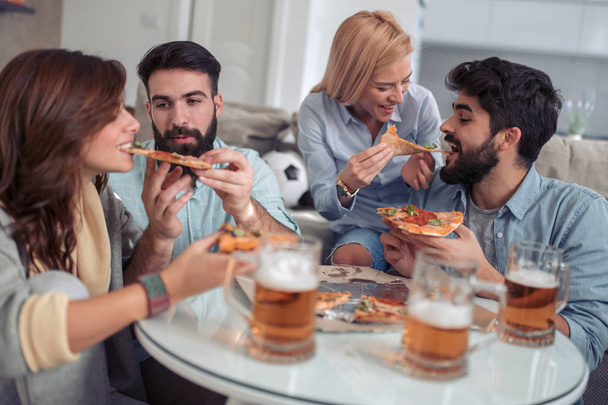 Groep jongeren pizza eten terwijl je samen plezier. - Foto, afbeelding