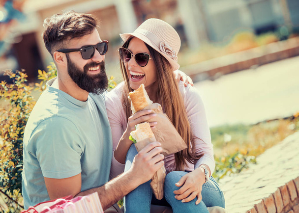 Couple eating sandwich outdoors,having fun together. - Photo, Image