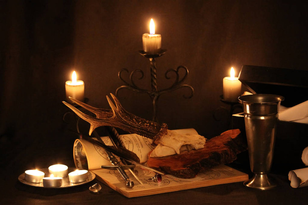 Mustan magian loitsuja. Wicca-loitsuja ja yrttejä. Still Live: Vanhat öljylamput, antiikkikirjat, kuivatut ruusunuput, palava kynttilä kuparikulhossa, lääkepullot, laventeli, Pulsatilla pratensis antiikkipohjalla. Wicca-tausta
. - Valokuva, kuva