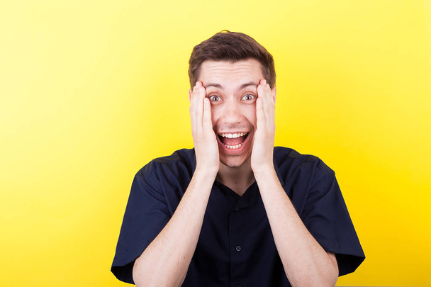 Excited man with hands on his face over yellow background - Photo, Image