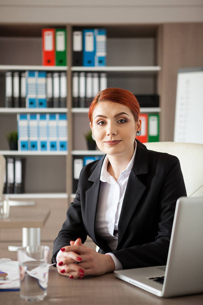 Redhead businesswoman alone in the office - Foto, afbeelding