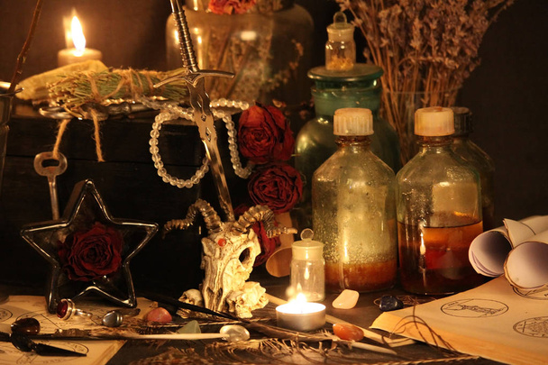 Černá magie kouzla. Wiccan kouzla a byliny. Stále Live: Staré olejové lampy, starožitné knihy, sušené růže poupata, hořící svíčka v měděnou mísu, lékovky, levandule, Pulsatilla pratensis na starožitný pozadí. Wicca pozadí. - Fotografie, Obrázek