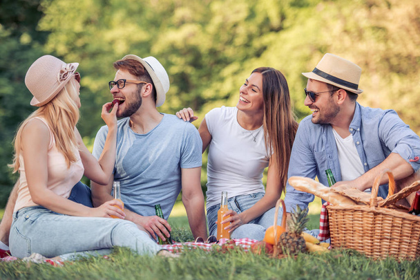 Mutlu genç arkadaşlarım parkta piknik. Onlar tüm mutlu, eğleniyor, gülümseyen ve gitar çalmak vardır. - Fotoğraf, Görsel