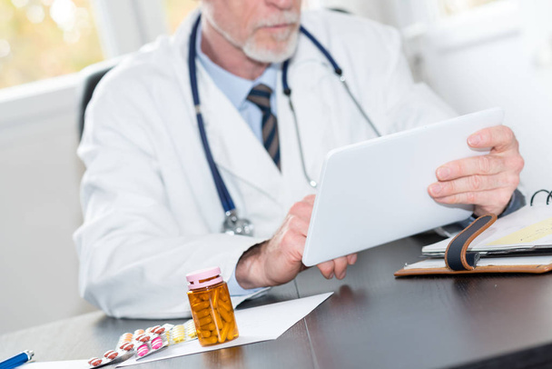 Ανώτερος γιατρός χρησιμοποιώντας tablet στο γραφείο - Φωτογραφία, εικόνα