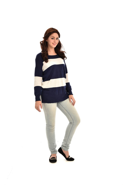 full length portrait of girl wearing striped blue and white jumper and jeans. standing pose on white studio background. - Foto, Imagem