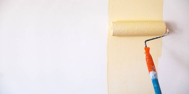 Colore giallo chiaro di colorazione della spazzola della vernice del rullo sullo sfondo bianco della parete
. - Foto, immagini