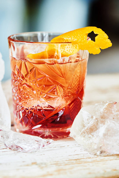 Alcoholic Negroni cocktail consisting of vermouth and liqueur with gin and citrus peel in glass beaker - Foto, afbeelding