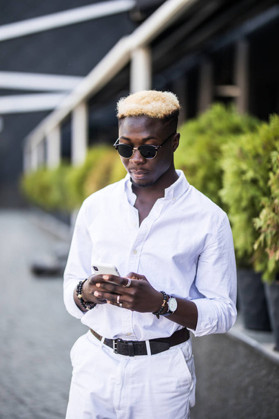 Vidám Afro-amerikai fiatalember ingyenes wi-fi használ rövid idő beszélgető barátokkal keresztül a társadalmi hálózatok, a mobiltelefon-portré - Fotó, kép