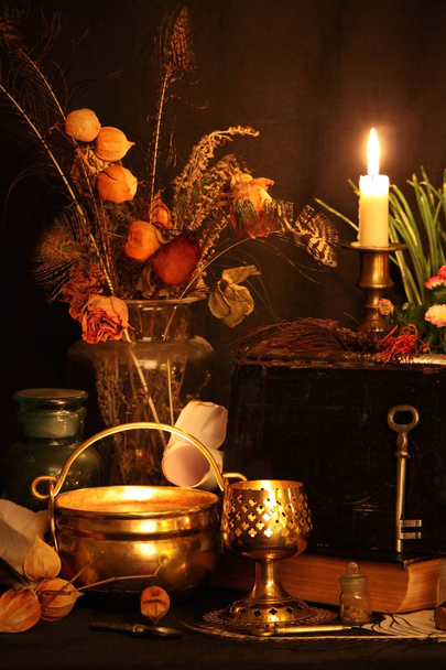 Black Magic varázsigék. Wiccan varázslatok és gyógynövények. Még élő: Régi olaj lámpa, antik könyvek, szárított Rózsa rügyek, egy égő gyertya egy réz tál, orvosságos-üvegek, levendula Pulsatilla pratensis egy antik háttér. Wicca háttér. - Fotó, kép