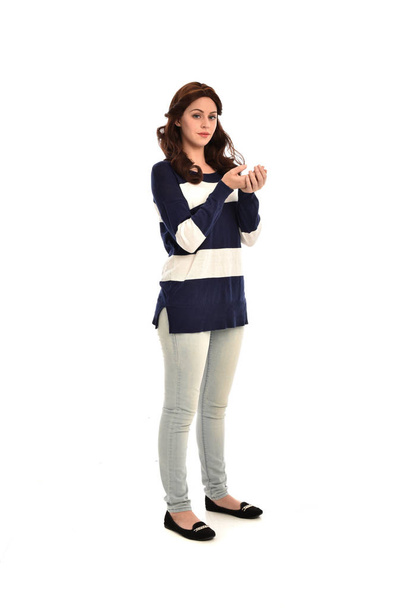 Ganzkörperporträt eines Mädchens in gestreiftem blau-weißen Pullover und Jeans. stehende Pose auf weißem Studiohintergrund. - Foto, Bild