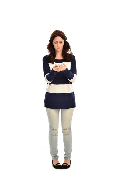 retrato de longitud completa de la niña con jersey a rayas azul y blanco y pantalones vaqueros. pose de pie sobre fondo blanco del estudio
. - Foto, imagen