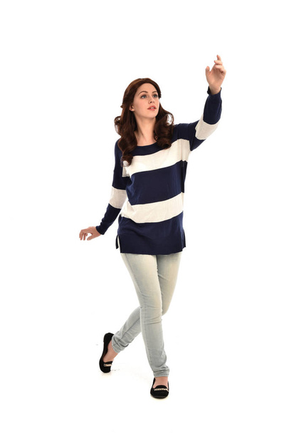 full length portrait of girl wearing striped blue and white jumper and jeans. standing pose on white studio background. - Photo, Image