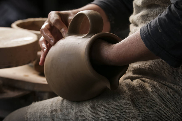 A raw clay pot in the hands of a potter. Workshop in the pottery workshop - Foto, Imagen