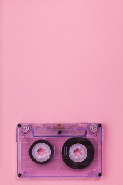 Компактна аудіокасета на рожевому фоні з великою кількістю копіювального простору вище
 - Фото, зображення