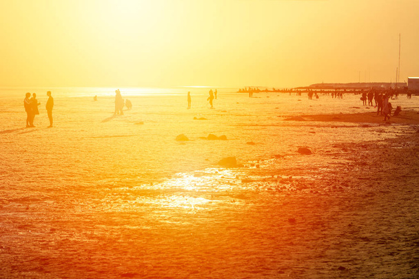 várias pessoas se encontram no pôr do sol do mar
 - Foto, Imagem