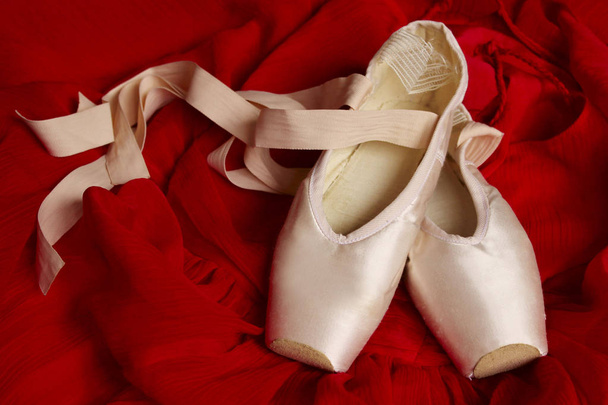Spitzenschuhe auf rotem Textilhintergrund. abstrakter Balletthintergrund. Ballett-Hintergrund. - Foto, Bild