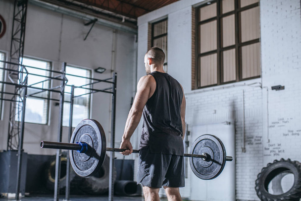 Back view of sportsman lifting weights at gym. - Φωτογραφία, εικόνα