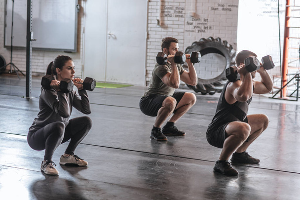 Group of men and women doing workouts together at gym. - Foto, immagini