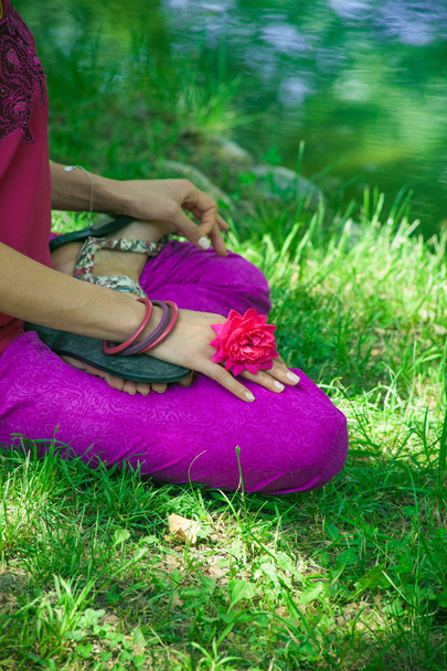 mulher corpo inferior em postura de lótus na grama por lago prática ioga dia de verão
 - Foto, Imagem