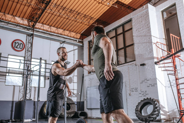 Two sportsmen greeting each other at gym. - Valokuva, kuva