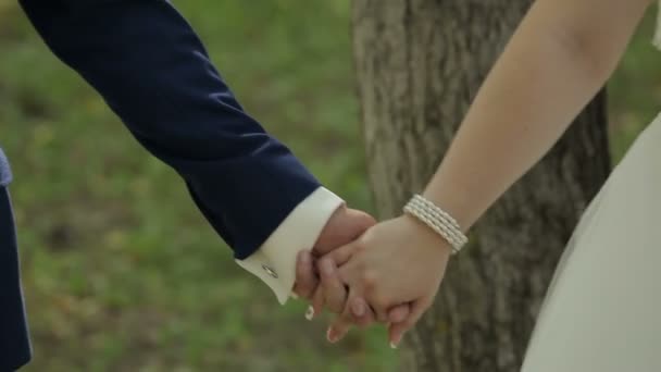緑の自然の背景の上に結婚指輪を交換する新郎新婦のクローズ アップ - 映像、動画