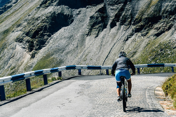 Вид ззаду жінка їде на велосипеді на гірській дорозі
 - Фото, зображення