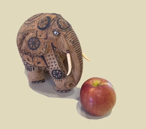 Sloní figurka z kokosového ořechu s červeným a žlutým jablkem - Fotografie, Obrázek