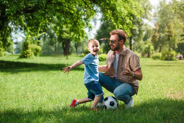 Gelukkig vader en zoon met voetbal bal in het park - Foto, afbeelding