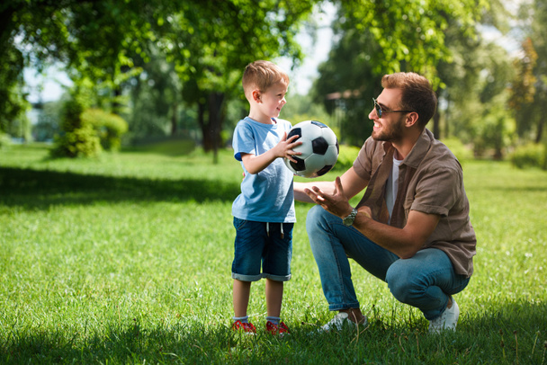 syn dává fotbalový míč k otci v parku - Fotografie, Obrázek