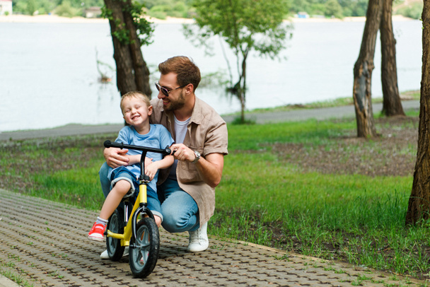 Glücklicher Vater bringt Sohn Fahrradfahren im Park bei - Foto, Bild