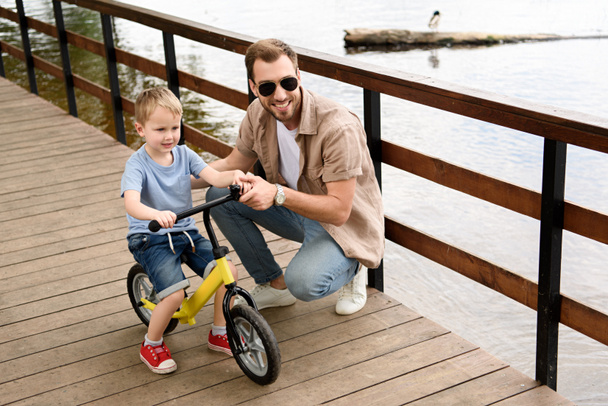 father teaching son riding bike at park - Photo, Image