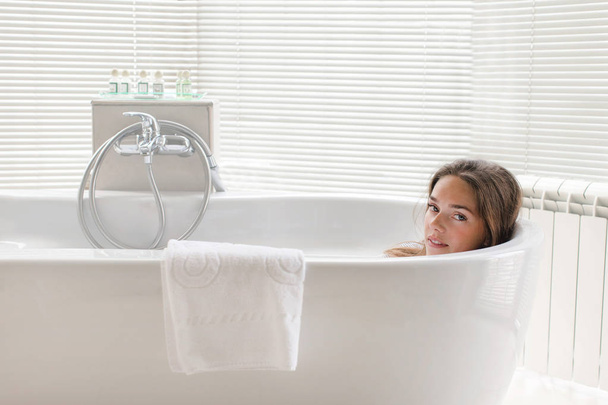 Beautiful young woman relaxing lying in bathtube - Photo, image