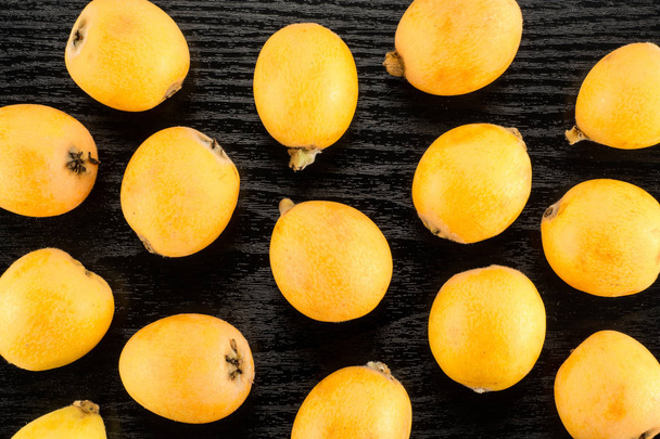 Fresh orange Japanese loquats flatlay isolated on black wood backgroun - Photo, Image