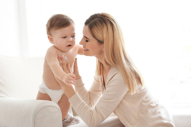 Woman applying body cream on her baby indoors - Fotografie, Obrázek