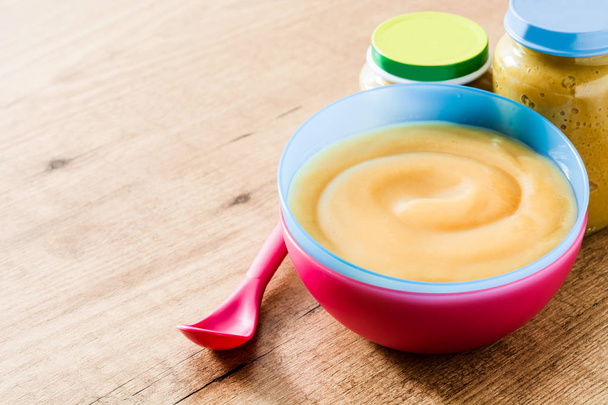 Żywności dla niemowląt: kolorowy miskę przecieru owocowego na drewnianym stole. Tło - Zdjęcie, obraz
