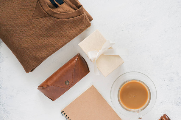 Camiseta masculina, caja de regalo, taza de café y cuaderno sobre fondo blanco. Enfoque selectivo, vista superior
 - Foto, Imagen
