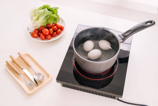 Three eggs boiling in pan with water - Φωτογραφία, εικόνα